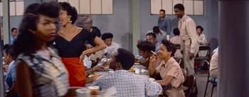 Movie still from “Carmen Jones” (1954), directed by Otto Preminger – A group of people sitting around a table eating; Medium shot, Over the shoulder angle