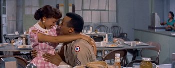 Movie still from “Carmen Jones” (1954), directed by Otto Preminger – A man and a woman sitting at a table in front of a table; Medium shot, Over the shoulder angle