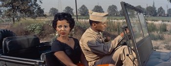 Movie still from “Carmen Jones” (1954), directed by Otto Preminger – A woman sitting next to a man in a uniform; Medium shot, High angle