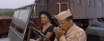 Movie still from “Carmen Jones” (1954), directed by Otto Preminger – A woman sitting next to a man smoking a cigarette; Medium shot, Low angle
