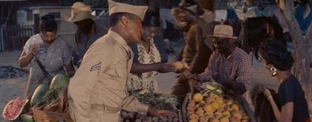 Movie still from “Carmen Jones” (1954), directed by Otto Preminger – A man in a military uniform handing a piece of food to a woman; Medium shot, High angle