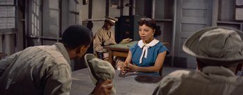 Movie still from “Carmen Jones” (1954), directed by Otto Preminger – A woman sitting at a table in front of two men; Medium shot, High angle