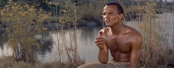 Movie still from “Carmen Jones” (1954), directed by Otto Preminger – A man sitting on the ground holding a spoon; Close Up shot, High angle