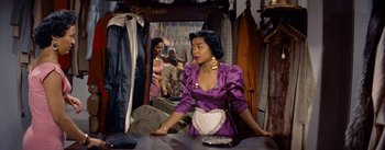 Movie still from “Carmen Jones” (1954), directed by Otto Preminger – A woman in a purple dress sitting in front of a mirror; Medium shot, Over the shoulder angle