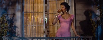 Movie still from “Carmen Jones” (1954), directed by Otto Preminger – A woman in a pink dress is drinking a beverage; Medium shot, Low angle