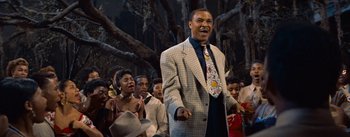 Movie still from “Carmen Jones” (1954), directed by Otto Preminger – A group of people standing in front of a tree; Medium shot, Low angle