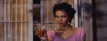 Movie still from “Carmen Jones” (1954), directed by Otto Preminger – A woman holding a glass of beer in her right hand; Close Up shot, Over the shoulder angle