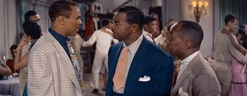 Movie still from “Carmen Jones” (1954), directed by Otto Preminger – A man in a blue suit and a pink tie; Medium shot, Over the shoulder angle
