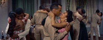Movie still from “Carmen Jones” (1954), directed by Otto Preminger – A man and a woman are kissing in a room; Medium shot, High angle