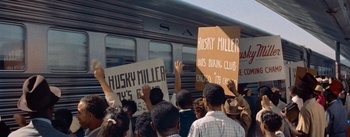 Movie still from “Carmen Jones” (1954), directed by Otto Preminger – A group of people standing next to a train; Medium shot, High angle