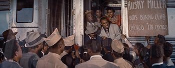 Movie still from “Carmen Jones” (1954), directed by Otto Preminger – A group of people standing around a train; Medium shot, High angle