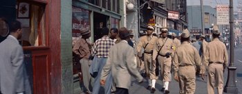 Movie still from “Carmen Jones” (1954), directed by Otto Preminger – A group of men walking down a street; Wide shot, High angle