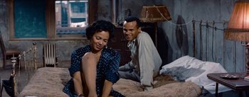 Movie still from “Carmen Jones” (1954), directed by Otto Preminger – A man and a woman sitting on a bed in a room; Medium shot, High angle