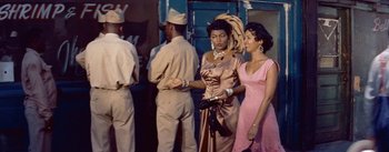 Movie still from “Carmen Jones” (1954), directed by Otto Preminger – A couple of women standing next to each other on a street; Medium shot, High angle