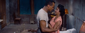 Movie still from “Carmen Jones” (1954), directed by Otto Preminger – A man and a woman holding each other's hands in front of a fireplace; Medium shot, Over the shoulder angle