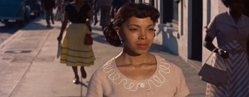 Movie still from “Carmen Jones” (1954), directed by Otto Preminger – A woman in a tan sweater with a white necklace; Close Up shot, Low angle