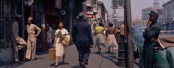 Movie still from “Carmen Jones” (1954), directed by Otto Preminger – A group of people walking down a street; Wide shot, High angle