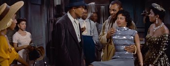 Movie still from “Carmen Jones” (1954), directed by Otto Preminger – A group of men standing next to each other in a room; Medium shot, Over the shoulder angle