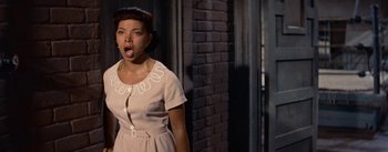 Movie still from “Carmen Jones” (1954), directed by Otto Preminger – A young woman in a tan dress with her mouth wide open; Medium shot, Low angle