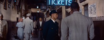 Movie still from “Carmen Jones” (1954), directed by Otto Preminger – A man in a uniform walking in a crowd; Medium shot, Low angle