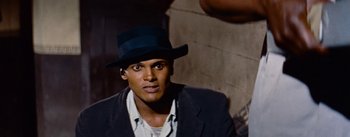 Movie still from “Carmen Jones” (1954), directed by Otto Preminger – A man wearing a black hat and a jacket; Close Up shot, High angle