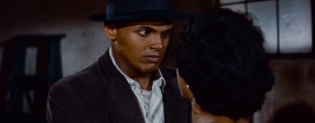 Movie still from “Carmen Jones” (1954), directed by Otto Preminger – A man wearing a black hat and a brown suit jacket; Close Up shot, Over the shoulder angle