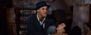 Movie still from “Carmen Jones” (1954), directed by Otto Preminger – A man and a woman are sitting on a couch; Medium shot, Overhead angle