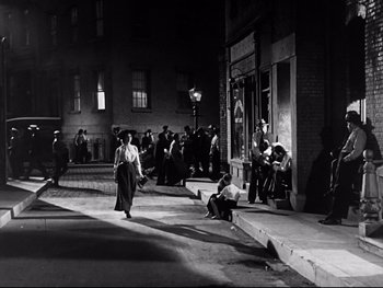 Movie still from “Carrie” (1952), directed by William Wyler – A black and white photo of people on the sidewalk; Wide shot, High angle