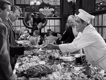 Movie still from “Carrie” (1952), directed by William Wyler – A black and white photo of people serving food; Medium shot, Over the shoulder angle