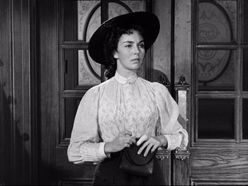 Movie still from “Carrie” (1952), directed by William Wyler – A woman wearing a hat and holding a purse; Medium shot, Low angle