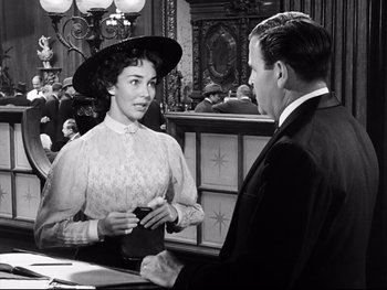 Movie still from “Carrie” (1952), directed by William Wyler – An old photo of a man and a woman talking to each other; Medium shot, Over the shoulder angle