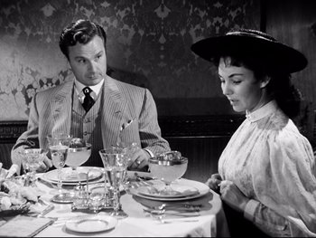 Movie still from “Carrie” (1952), directed by William Wyler – A man and a woman sitting at a dinner table; Medium shot, High angle
