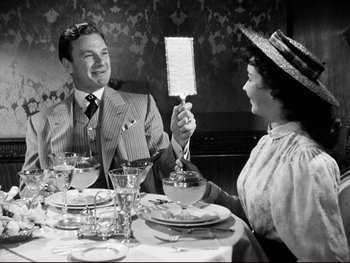 Movie still from “Carrie” (1952), directed by William Wyler – A man and a woman sitting at a dinner table; Medium shot, Over the shoulder angle
