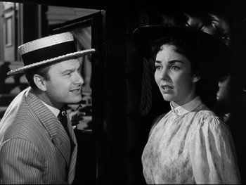 Movie still from “Carrie” (1952), directed by William Wyler – A man and a woman standing next to each other; Medium shot, Over the shoulder angle