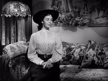 Movie still from “Carrie” (1952), directed by William Wyler – A woman in a black dress and a black hat; Medium shot, Low angle