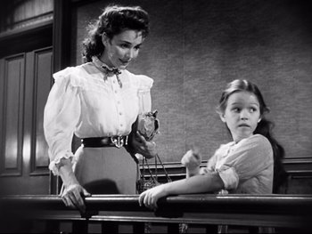 Movie still from “Carrie” (1952), directed by William Wyler – A woman and a little girl sitting next to a railing; Medium shot, Low angle