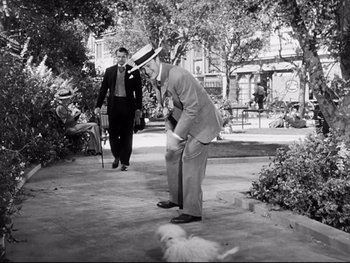 Movie still from “Carrie” (1952), directed by William Wyler – A man in a suit and hat is playing a game of croquet; Wide shot, High angle