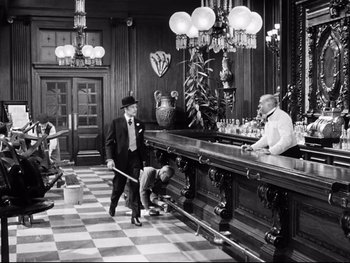 Movie still from “Carrie” (1952), directed by William Wyler – Two men in suits and ties at a bar; Wide shot, High angle