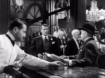 Movie still from “Carrie” (1952), directed by William Wyler – A group of men standing around a bar; Medium shot, Over the shoulder angle