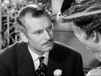 Movie still from “Carrie” (1952), directed by William Wyler – A black and white photo of a man in a suit and tie; Close Up shot, Over the shoulder angle