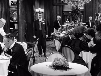 Movie still from “Carrie” (1952), directed by William Wyler – A black and white photo of people sitting at a table; Wide shot, High angle
