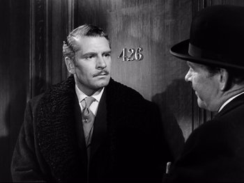 Movie still from “Carrie” (1952), directed by William Wyler – A man in a suit and tie standing next to another man in a hat; Close Up shot, Over the shoulder angle