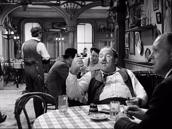 Movie still from “Carrie” (1952), directed by William Wyler – An old photo of a man sitting at a table in a restaurant; Medium shot, Over the shoulder angle