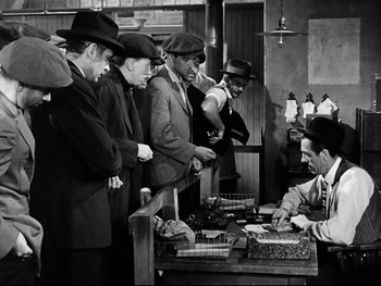 Movie still from “Carrie” (1952), directed by William Wyler – A group of men standing around a table; Medium shot, High angle