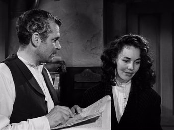 Movie still from “Carrie” (1952), directed by William Wyler – A man and a woman are looking at a newspaper; Medium shot, Over the shoulder angle