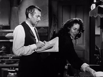 Movie still from “Carrie” (1952), directed by William Wyler – A man and a woman standing next to each other in a room; Medium shot, Over the shoulder angle