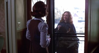 Movie still from “Carrie” (1976), directed by Brian De Palma – A woman standing in front of a mirror holding a cup; Medium shot, Over the shoulder angle