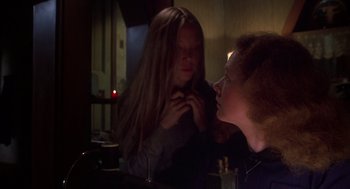 Movie still from “Carrie” (1976), directed by Brian De Palma – A woman looking in the mirror while another woman looks on; Close Up shot, Over the shoulder angle