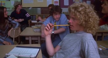 Movie still from “Carrie” (1976), directed by Brian De Palma – A man holding a pencil in a classroom while another man watches; Medium shot, Over the shoulder angle