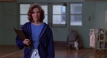 Movie still from “Carrie” (1976), directed by Brian De Palma – A woman standing in a room holding a book; Medium shot, Low angle